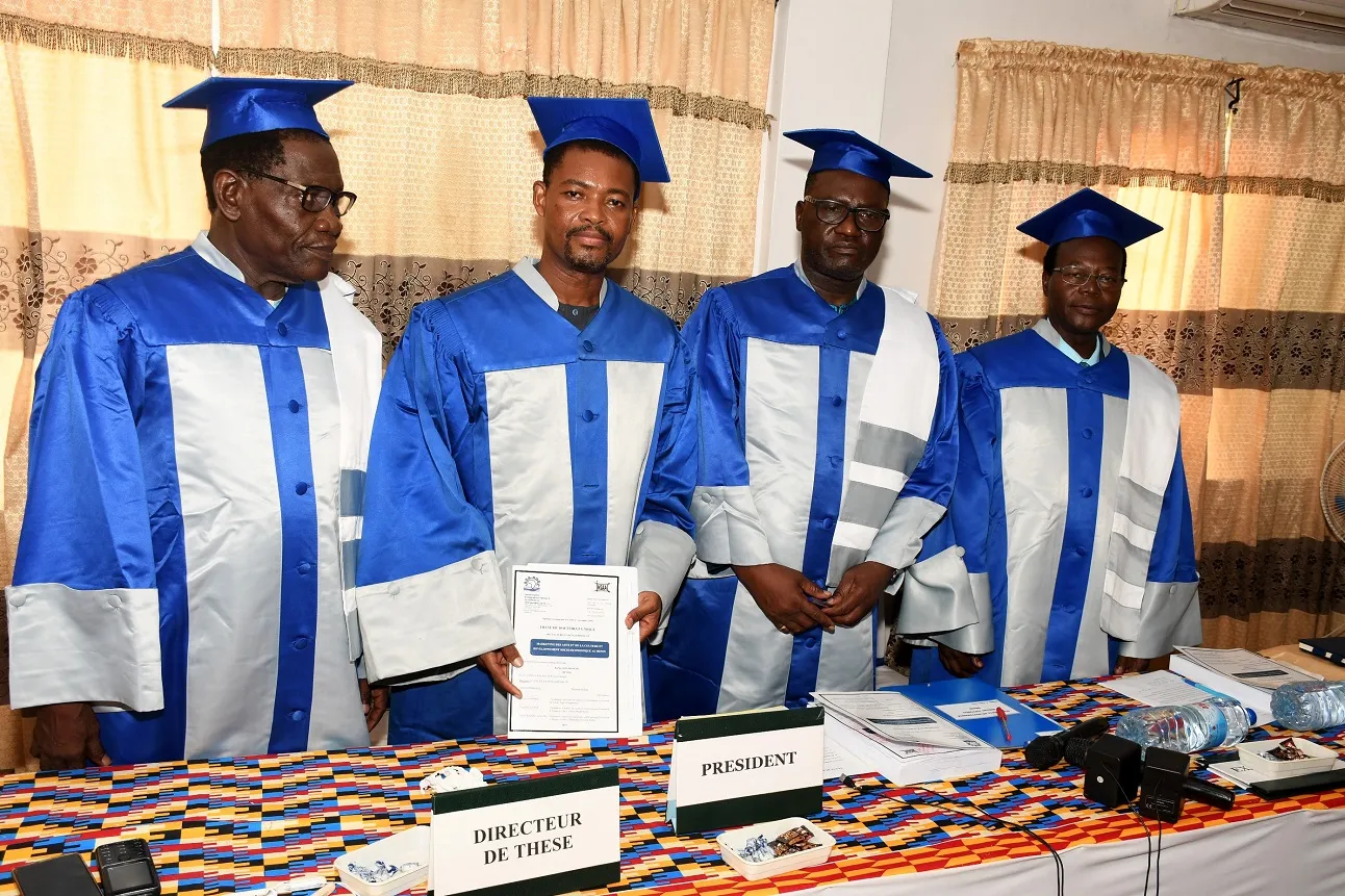 Le nouveau docteur vêtu de sa toge au milieu de trois des membres du jury