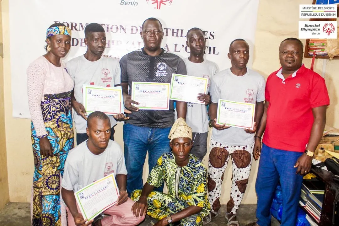 Des athlètes vivant avec des déficiences mentales ou intel- lectuelles en présence du formateur (extrême gauche) et de la  directrice des sports (extrême droite)